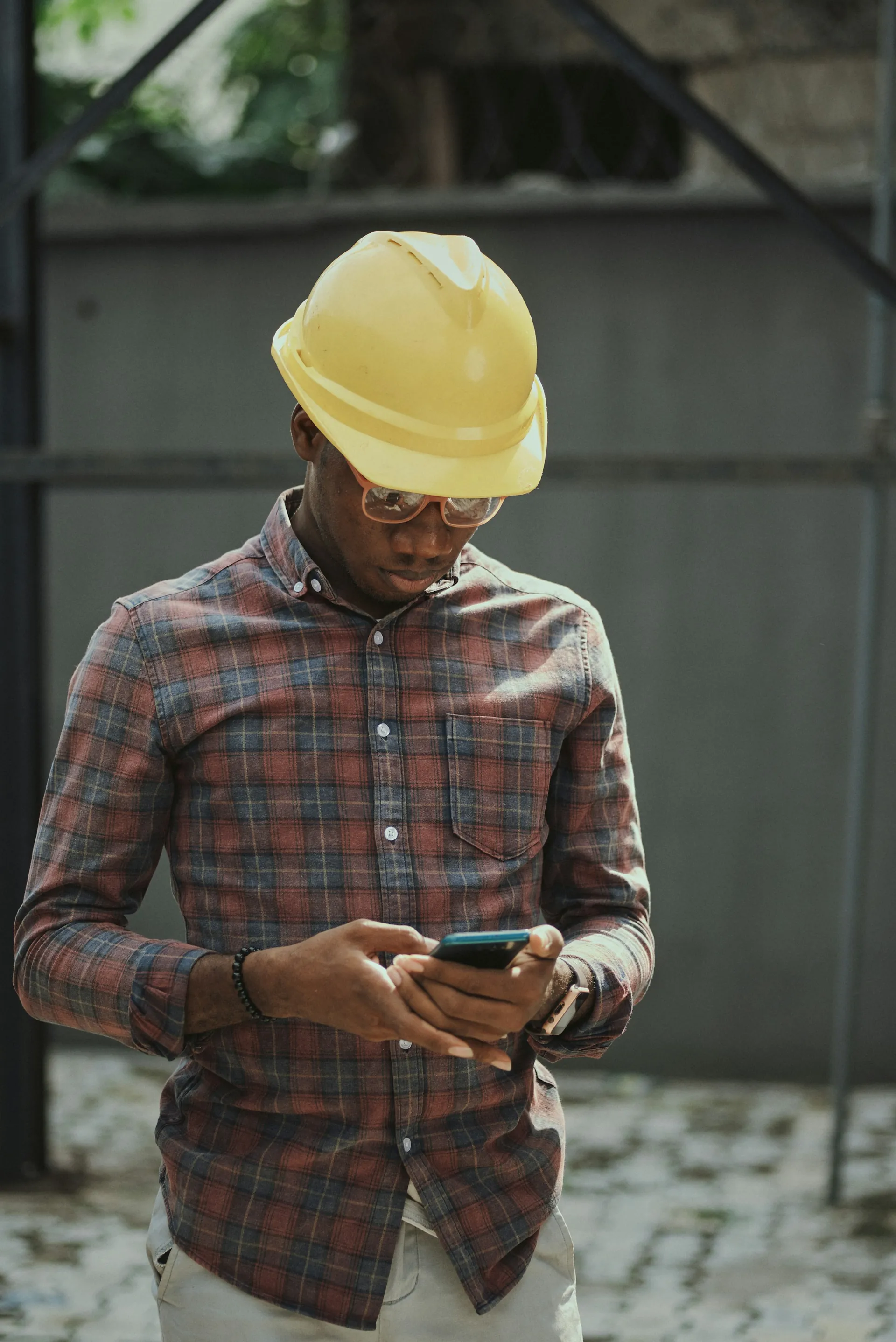 Field technician in a hard hat checking data on a phone