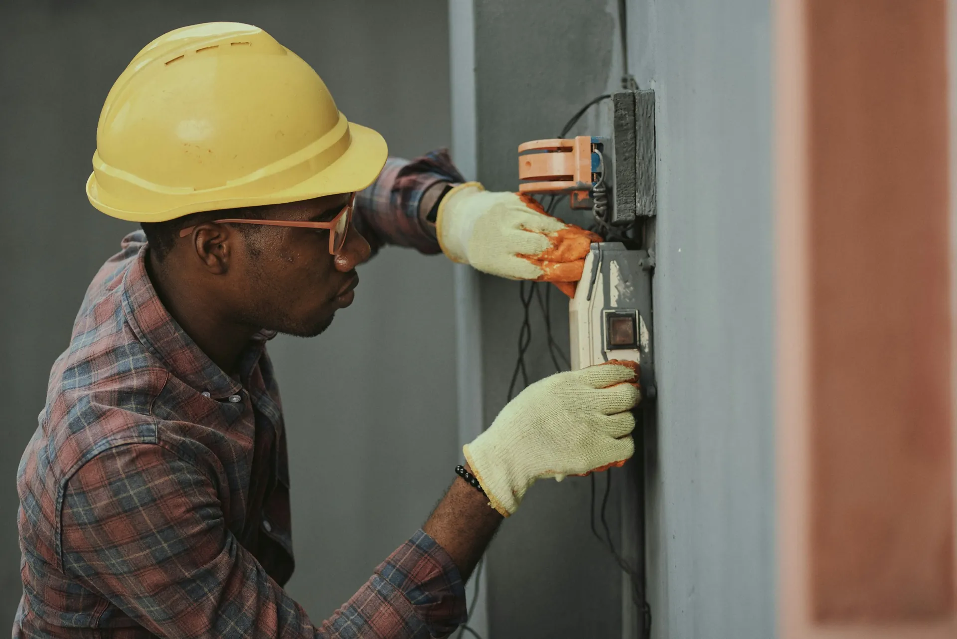 Technician in a hard hat working on an electrical panel